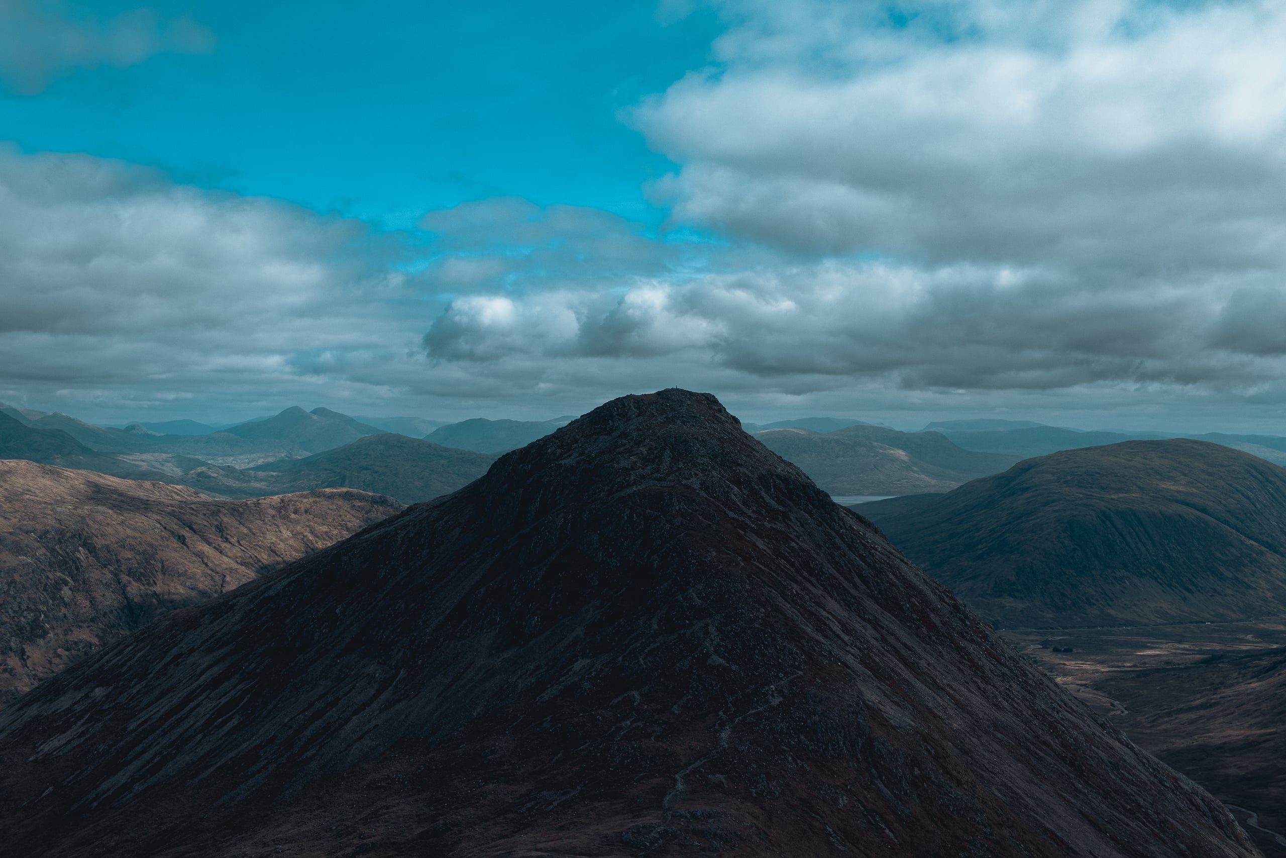 Highland mountain pyramid against clouded sky, mirrored composition